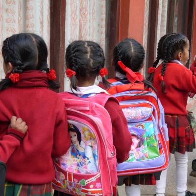Students in Nepal wait patiently in a line for their Childcare volunteer Children line up with their backpacks outside their classroom in Nepal